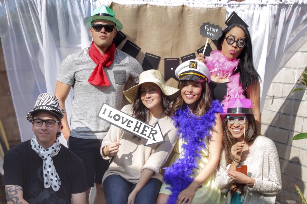 A group of young men and women are posing at a party photo booth.
